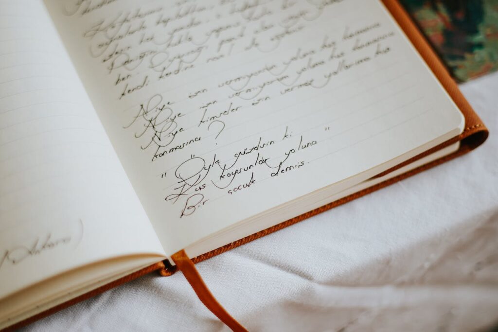 High-angle view of an open notebook with handwritten text on a white tablecloth, suggesting warmth and creativity.
